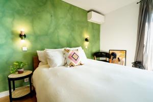 een slaapkamer met een wit bed en een groene muur bij Ocean Breeze Retreat near Ericeira in Carvoeira