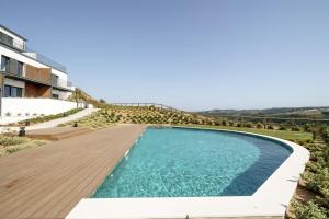 een zwembad met een houten terras en een gebouw bij Ocean Breeze Retreat near Ericeira in Carvoeira