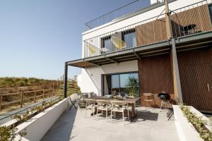 een patio met een tafel en stoelen in een gebouw bij Ocean Breeze Retreat near Ericeira in Carvoeira