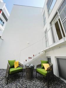 un patio con 2 sedie verdi e un tavolo di Yama no Shita Homestay a Zhongpu