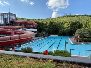 ein großes Schwimmbecken mit Wasserrutsche in der Unterkunft Pension OTTO in Netphen
