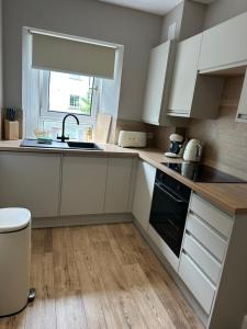 a kitchen with white cabinets and a sink at BOFA Snug Apartment in Bridge of Allan