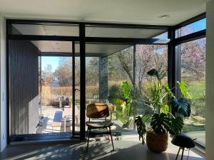 a glass room with a chair and a window at Modern Beach House At Skæring Beach in Egå +12 photos