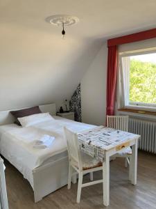 a bedroom with a bed and a table and a window at Café Pension Pfaus 1 fewo-4 Zimmer in Mühlenbach