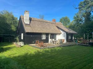 a small house with a yard with chairs and tables at Thatched Cottage Between Tisvilde And Liseleje in Frederiksværk