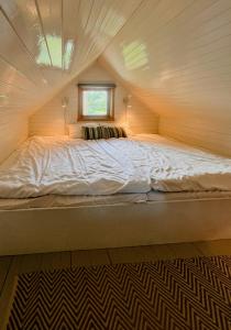 un lit dans une petite maison avec une fenêtre dans l'établissement Northern Lights At Stetind Fishermans Cabin, à Storjord I Tysfjord