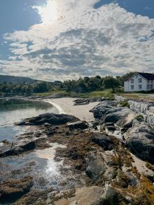une maison sur la rive d'une plage avec des rochers dans l'établissement Northern Lights At Stetind Fishermans Cabin, à Storjord I Tysfjord