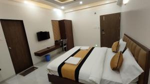 a bedroom with a large bed and a television at Hotel Grand Lushwood in Aurangabad
