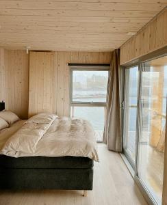a bedroom with a bed and a large window at Architectural Gem On Rocks In Kvenvær in Kvenvær