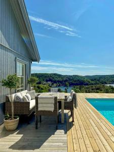 een patio met een tafel en een bank op een houten terras bij Modern Summer House With Pool In Risør in Risør