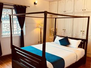 una camera da letto con letto a baldacchino nero e cuscini blu di PSR Rooms and Cottages a Ooty