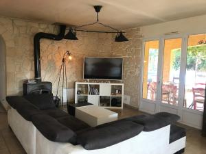ein Wohnzimmer mit Couch und Flachbildfernseher in der Unterkunft Villa climatisée avec grande piscine in Le Pouget