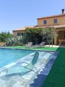 ein Swimmingpool mit einem Stuhl und einem Haus in der Unterkunft Villa climatisée avec grande piscine in Le Pouget
