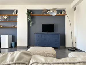 a living room with a tv and a blue dresser at Matteotti 17 Easy in Cinisi