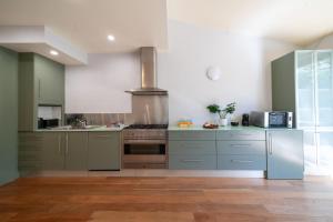 cocina con armarios grises y horno con fogones en Marvelous Manly Home moments from the Beach - NEW, en Sídney