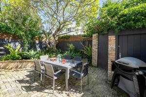 Un patio con mesa y sillas y parrilla. en Marvelous Manly Home moments from the Beach - NEW, en Sídney