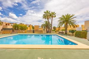 Una gran piscina con palmeras y edificios. en Bungalow Salud - PlusHolidays, en Calpe