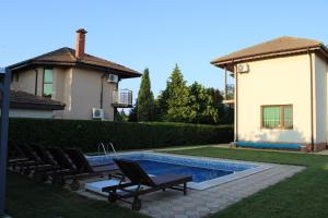 a pool with lounge chairs next to a house at Къща за гости ,,Ива'' in Bŭlgarevo