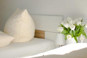 a bed with a vase of white flowers on it at Weidestr 18 Wohnung 2 ( Captains' finest) in Heiligenhafen