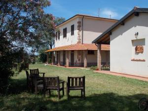 twee banken in het gras voor een gebouw bij Agriturismo Contessa Beatrice in San Vincenzo