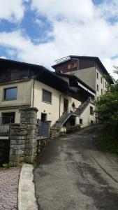 a building with a stone wall and stairs next to a street at Albergo Ristorante Sciatori in Pievepelago