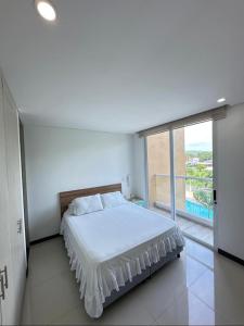 Estación El SaltoにあるHermoso Apartamentoのベッドと大きな窓のある白い寝室