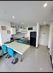 Estación El SaltoにあるHermoso Apartamentoのキッチン(白いテーブル、青い椅子付)