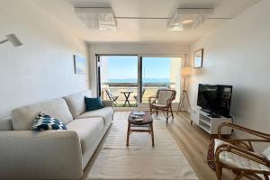 a living room with a couch and a television at Vue mer 180 - Charmant T3 - Coup de coeur garanti in Ploemeur
