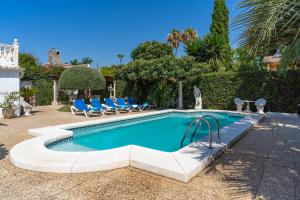 Una piscina con sillas azules al lado de una casa. en Lovely Villa Las Palmeras, en Marbella