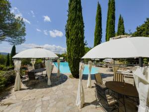 a patio with tables and umbrellas next to a pool at Ferienwohnung Fortuna del Lupo mit Pool und Aussicht in Subbiano
