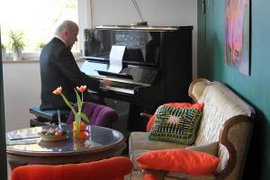 a man playing a piano in a living room at Café Pension Pfaus Heidburg in Mühlenbach