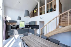 a kitchen and dining room with a wooden table and stairs at Ferienhaus Sanddornweg 06 mit Klimaanlage & E-Ladestation in Mistelgau +4 photos
