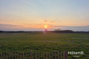 a sunset in a field with a fence at Cottage Mamie Yvette Private Spa in Blanc +36 photos