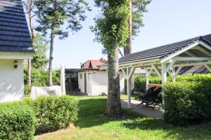 une pergola blanche dans une cour avec un arbre dans l'établissement Madleen, à Wieck