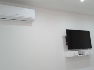 Un televisor de pantalla plana pegado a una pared blanca. en chambre chez alcinda, en Mindelo