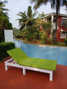 a green bench sitting next to a swimming pool at Sun-kissed Holidays Goa-Sapphire in Siolim