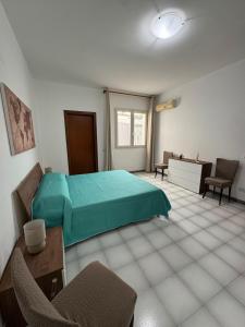 a bedroom with a green bed and a desk and chairs at Il cortiletto in Menfi
