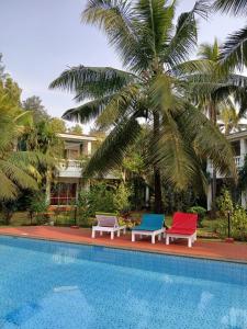a group of chairs sitting next to a swimming pool at Sun-kissed Holidays Goa-Sapphire in Siolim