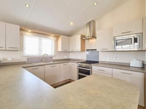 a kitchen with white cabinets and a sink and a microwave at Host & Stay - Clearwater Willerby Lodge in Isle of Sheppey