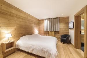 una camera da letto con un letto bianco e una sedia di Pas de l’Ourson - Megève - Chalet with Sauna a Megève