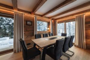 una sala da pranzo con tavolo, sedie e finestre di Pas de l’Ourson - Megève - Chalet with Sauna a Megève