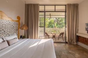 a bedroom with a bed and a balcony with a table at La Sataqui in Cansaulim