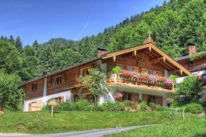 a large wooden house with a balcony on a mountain at Ferienwohnungen Kimpfbeck, Kreuth-Schärfen in Kreuth