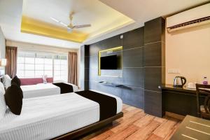 a hotel room with two beds and a television at Hotel O The Nest By Mint in Siliguri