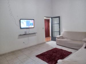 a living room with a couch and a flat screen tv at Hospedagem Alvinópolis in Atibaia