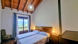 Un dormitorio con una cama y una ventana grande. en El Jardin del Erizo, en Llanes