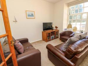 ein Wohnzimmer mit 2 Ledersofas und einem TV in der Unterkunft Stable Cottage in Ventnor
