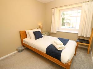 Schlafzimmer mit einem Bett, einem Fenster und einem Stuhl in der Unterkunft Stable Cottage in Ventnor