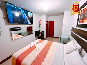 a bedroom with a bed and a tv on the wall at Veneccia Gold Hotel in Chiclayo
