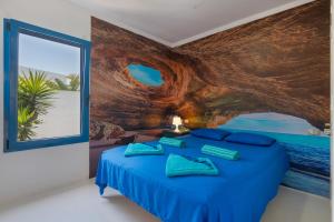 a bedroom with a blue bed with a painting on the wall at Villa Lunamoon, Playa Blanca in Playa Blanca +23 photos